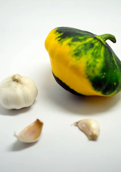 Calabaza manchada sobre un fondo blanco y ajo — Foto de Stock