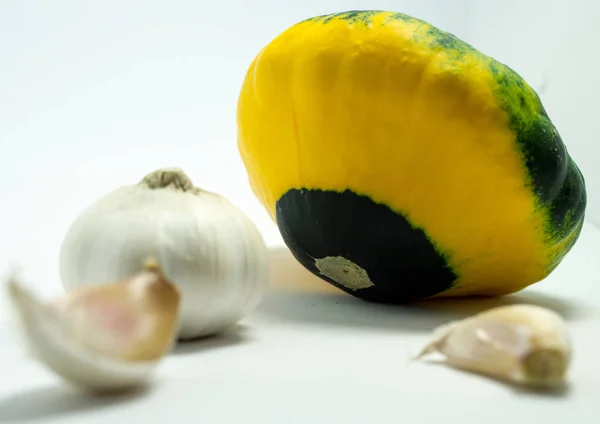 Calabaza manchada sobre un fondo blanco y ajo — Foto de Stock