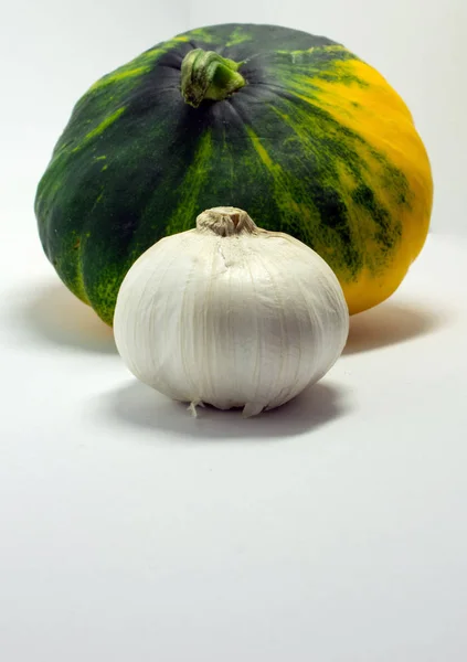 Calabaza manchada sobre un fondo blanco y ajo — Foto de Stock