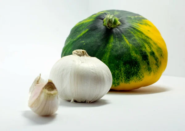 Calabaza manchada sobre un fondo blanco y ajo — Foto de Stock