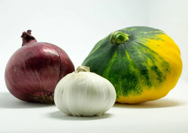 Gefleckter Kürbis auf weißem Hintergrund, Zwiebeln und Knoblauch — Stockfoto