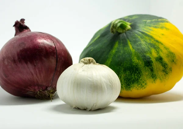 Gefleckter Kürbis auf weißem Hintergrund, Zwiebeln und Knoblauch — Stockfoto