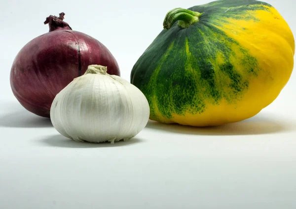 Gefleckter Kürbis auf weißem Hintergrund, Zwiebeln und Knoblauch — Stockfoto