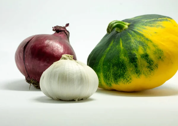 Calabaza manchada sobre un fondo blanco, cebolla y ajo — Foto de Stock