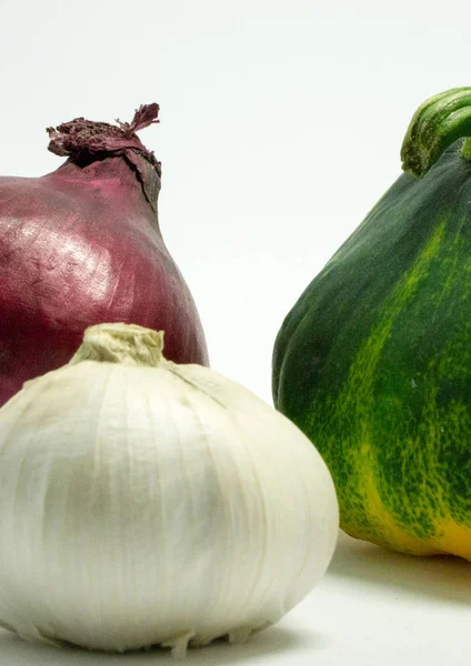 Abóbora manchada em um fundo branco, cebola e alho — Fotografia de Stock