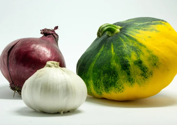 Gefleckter Kürbis auf weißem Hintergrund, Zwiebeln und Knoblauch — Stockfoto