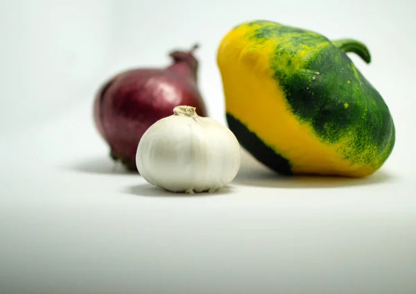 Calabaza manchada sobre un fondo blanco, cebolla y ajo — Foto de Stock