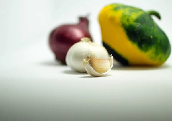 Calabaza manchada sobre un fondo blanco, cebolla y ajo — Foto de Stock