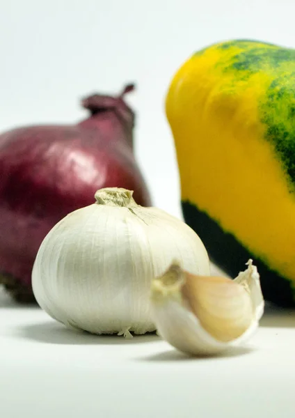 Abóbora manchada em um fundo branco, cebola e alho — Fotografia de Stock