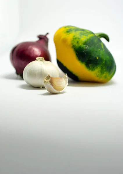 Calabaza manchada sobre un fondo blanco, cebolla y ajo — Foto de Stock