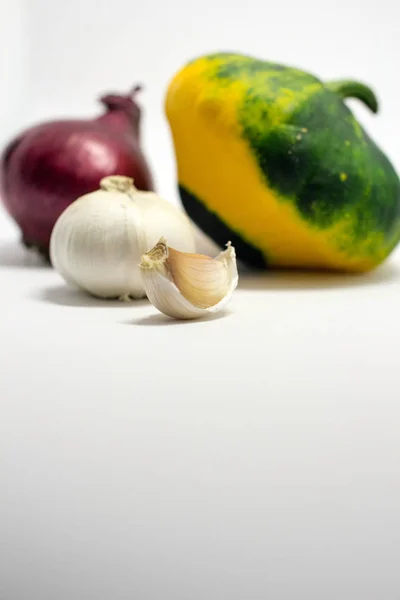 Abóbora manchada em um fundo branco, cebola e alho — Fotografia de Stock