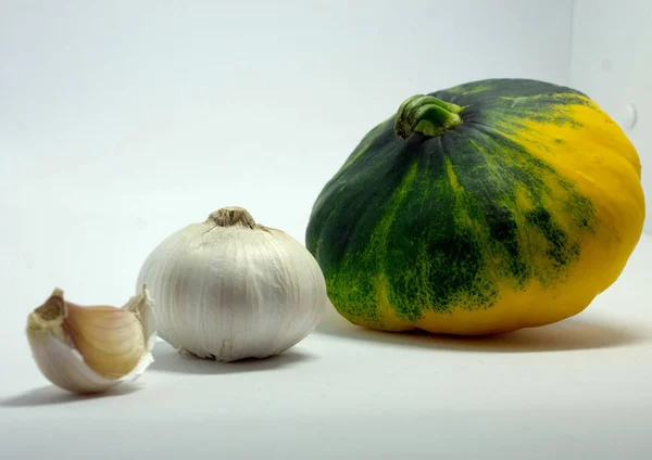 Calabaza manchada sobre un fondo blanco y ajo — Foto de Stock