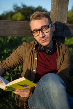 Mavi gökyüzü arka plan üzerinde kitap okuma gözlük bir adam portresi.