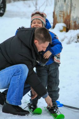 2012.01.01, Maloyaroslavets, Rusya. Oğullarının kayak yapmasına yardım eden genç bir adam. Rus çocukların kış eğlencesi.