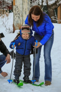 2012.01.01, Maloyaroslavets, Rusya. Anne ve baba oğullarının kayak yapmasına yardım ediyor. Rus çocukların kış eğlencesi.