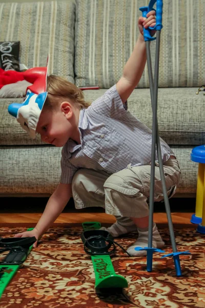 2012.01.01, Maloyaroslavets, Russia. A little boy in a smurf mask put on skis in a room at home.