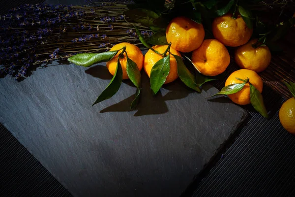 still life with lavender and tangerines in a dark key. composition of flowers and fruits for decoration cards.