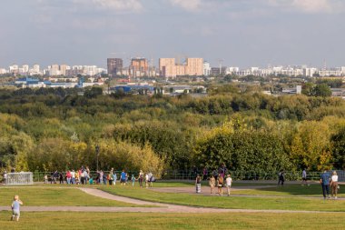 2019.09.01, Moskova, Rusya. Çinli turistler, Kolomenskoye parkındaki eski bir kilisenin arka planında şemsiye altında yürüyorlar..