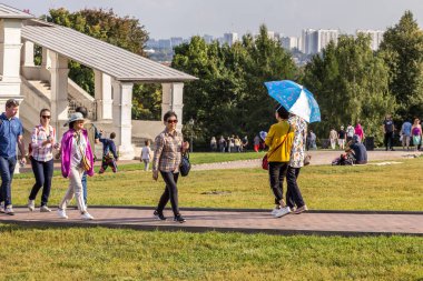 2019.09.01, Moskova, Rusya. Çinli turistler, Kolomenskoye parkındaki eski bir kilisenin arka planında şemsiye altında yürüyorlar..