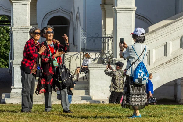 2019.09.01, Moskova, Rusya. Çinli turistler birbirlerini Kolomenskoye parkındaki eski bir kilisenin arka planında fotoğraflıyorlar..