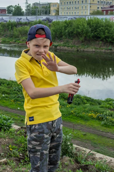 2019 10ロシア トゥーラ州 黄色のポロシャツと野球帽を着た少年が川岸で遊んでいる — ストック写真