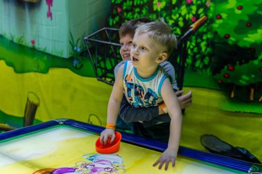 2019.02.10, Maloyaroslavets, Rusya. Bir ağabey, küçüklerin hava hokeyi, bulanıklık ve tahıl efekti oynamasına yardım eder. Çocukların aktif yaşam tarzı.