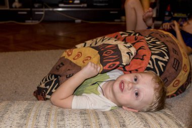 2019.01.03, Maloyaroslavets, Rusya. Evde eğlenen küçük bir çocuk. Yerde yatan gülen bir çocuk, bulanık ve tahıl etkisi.