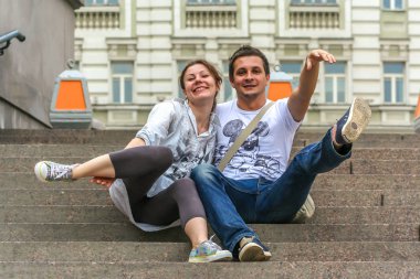 2011.05.21, Moscow, Russia. A young man and woman sitting on the stone staircase and having fun.