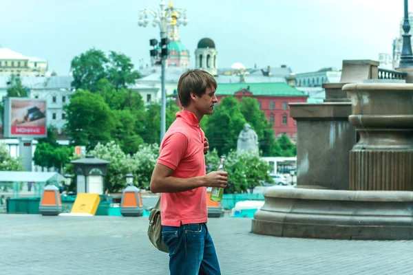 2011.05.21, Moscow, Russia. A single young man wearing pink polo having fun by the square, side view.