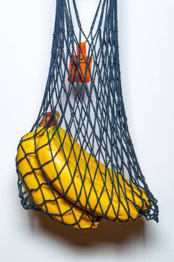 bunch of ripe bananas in a handmade cotton bag on a white background. eco-friendly packaging concept for products.