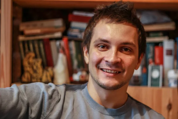 Retrato Joven Sonriente Casa Fondo Estantería Mirando Cámara Tipo Divirtiéndose — Foto de Stock