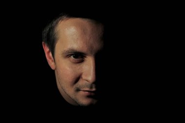 Karanlık anahtarı olan genç bir adamın portresi. Siyah arka plandaki adamın portresi. Erkeğin duyguları kavramı.