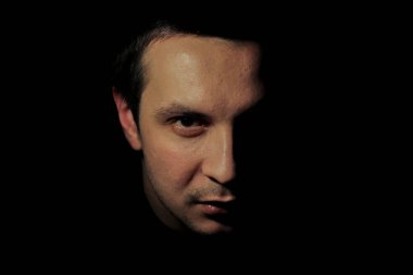 Karanlık anahtarı olan genç bir adamın portresi. Siyah arka plandaki adamın portresi. Erkeğin duyguları kavramı.