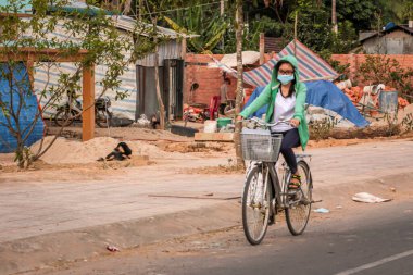 304.2015, Phan Thiet, Vietnam. Ulusal koni şeklinde şapkalı yerel Vietnamlılar yolda bisiklet sürüyor..