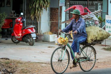 304.2015, Phan Thiet, Vietnam. Ulusal koni şeklinde şapkalı yerel Vietnamlılar yolda bisiklet sürüyor..