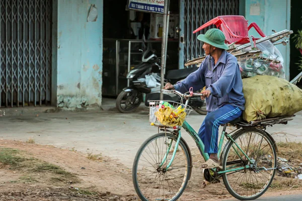 304.2015, Phan Thiet, Vietnam. Ulusal koni şeklinde şapkalı yerel Vietnamlılar yolda bisiklet sürüyor..