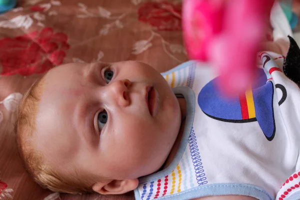 Menino Recém Nascido Deita Costas Cama Olha Para Brinquedos Pendurados — Fotografia de Stock