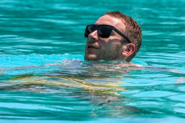 Havuzda yüzen genç bir adamın başı. Dinlenme zamanı..