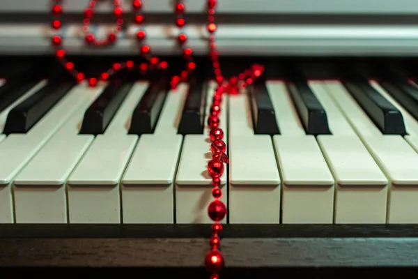 Красные Бусины Рождественские Украшения Лежат Случайно Клавиатуре Фортепиано — стоковое фото