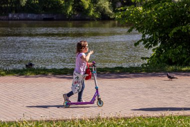 26.05.2018, Moskova, Rusya. Nehir boyunca scooter süren küçük bir kız.