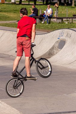26.05.2018, Moskova, Rusya. Kırmızı tişörtlü genç bir çocuk kaykay parkında özel bir bisikletle numaralar yapıyor. Modern Rus çocuklarının aktif yaşam tarzı.