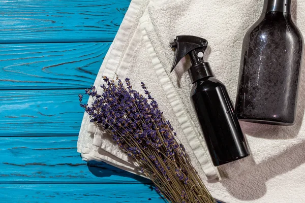 Banyo aksesuarları ve bir demet lavanta mavi ahşap arka planda katlanmış beyaz havluların üzerinde uzanır.. 