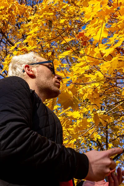 Mladý Blonďák Krátkými Vlasy Slunečními Brýlemi Černou Bundou Kouřící Podzimním — Stock fotografie