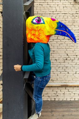 Maskeli kadın. Metal inşaatında büyük bir gagası olan parlak renkli kuş kafalı. Tatil için ev yapımı orijinal kostüm..