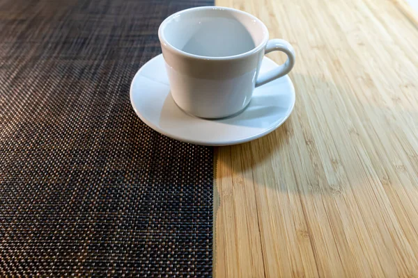 Empty white cup and saucer stands on a two-color background on the table.