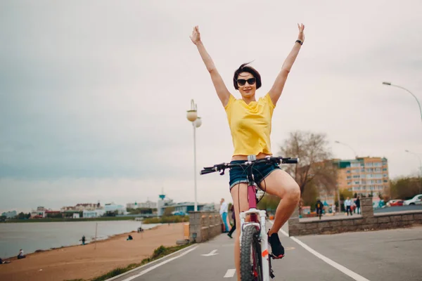 Young female hands up on bicycle outdoor