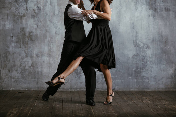 Молодая красивая женщина в черном платье и мужчина танго
