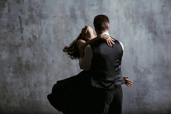 年轻俏丽的妇女在黑礼服和人舞蹈探戈 — 图库照片