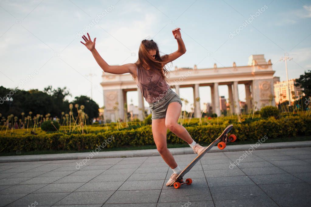 Young sporty woman riding on the longboard in the park