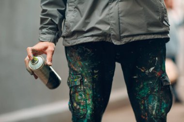 Grafiti sanatçısı elinde boya spreyi ile giysiler içinde.